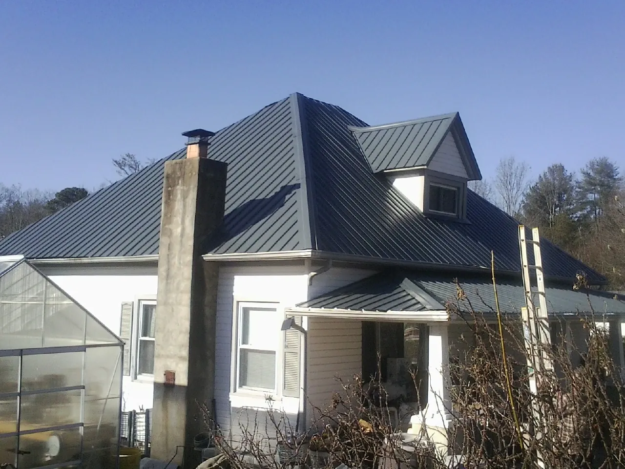 Dark blue standing seam metal roof on a white farmhouse with dormer — Slate & Tile Roof Repair by Roofing Brothers in Rome City