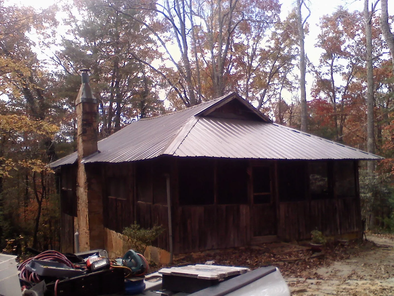 Brown metal hip roof on an old cabin with a stone chimney in Rome City