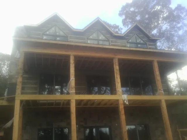 Dormers and porch framing on a large log home under construction — Roof Coating work by our crew in Rome City