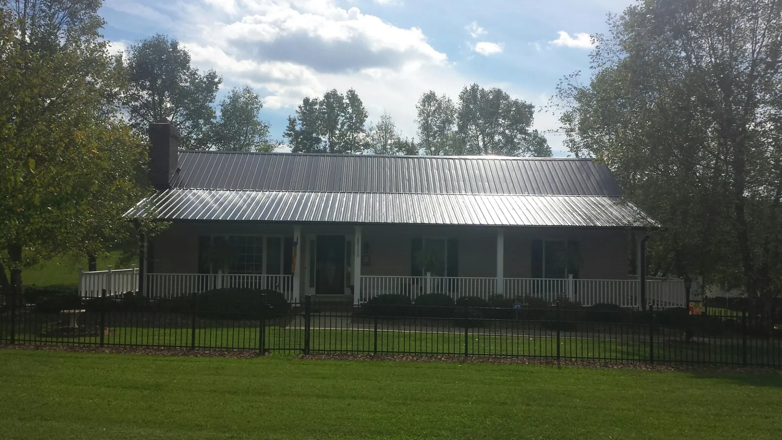Gray metal roof on a brick ranch with a full width front porch — Gutter Guard Installation work by our crew in Rome City