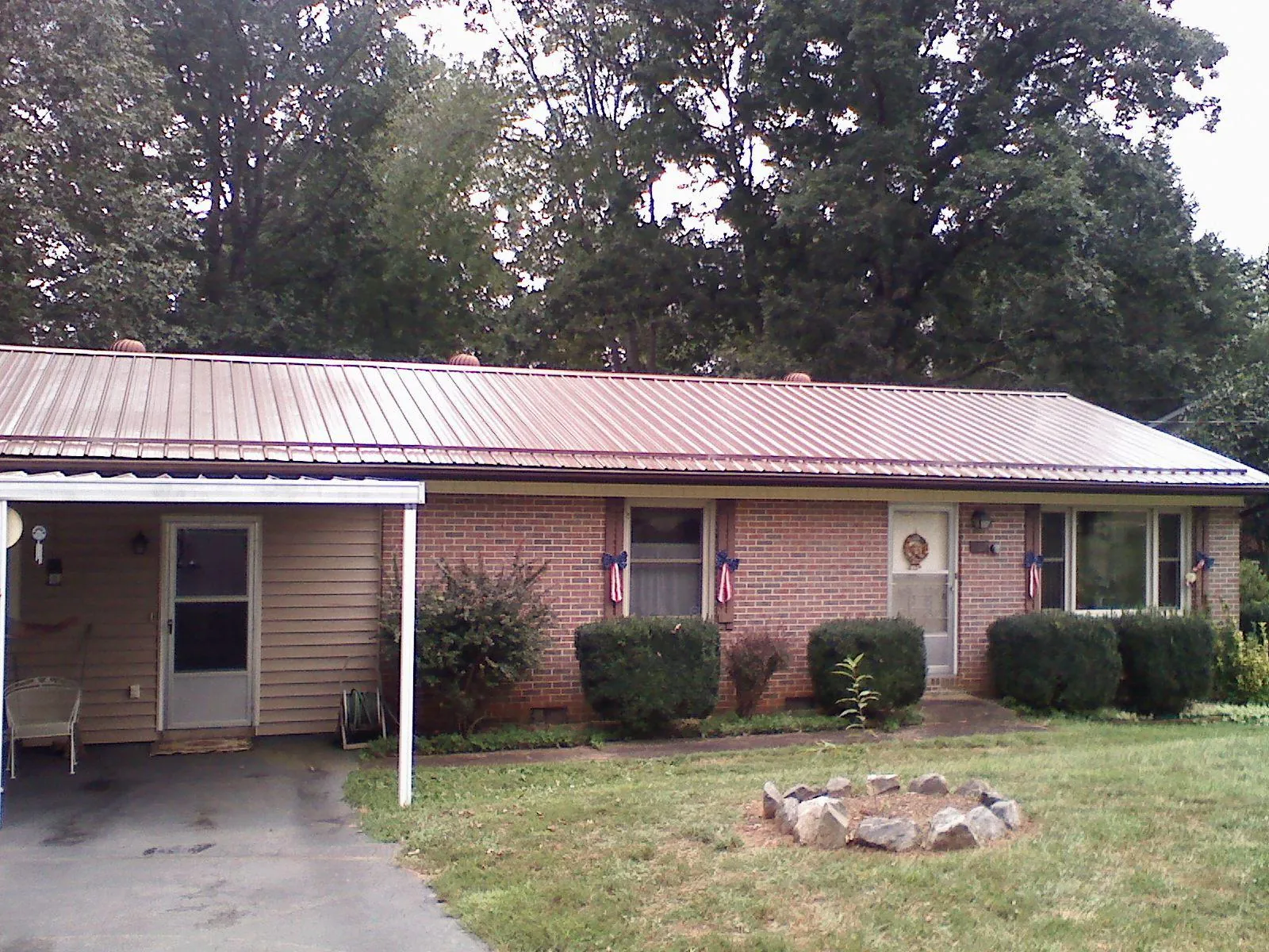 Bronze metal roof and carport on a brick ranch home — Roof Repair work by our crew in Rome City