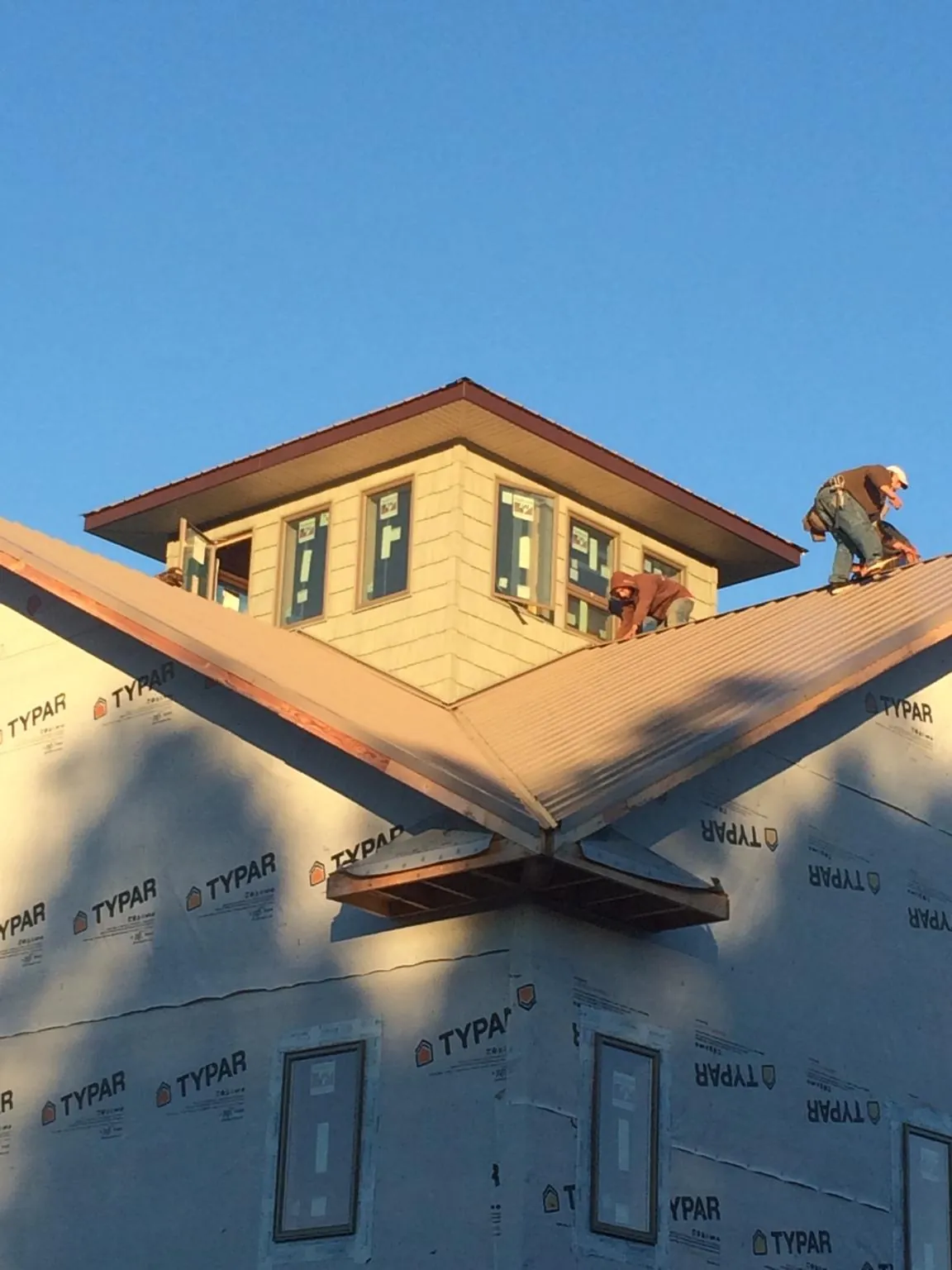 Roofers working around a rooftop cupola on a new metal roof at sunset — Roof Waterproofing in Rome City by Roofing Brothers